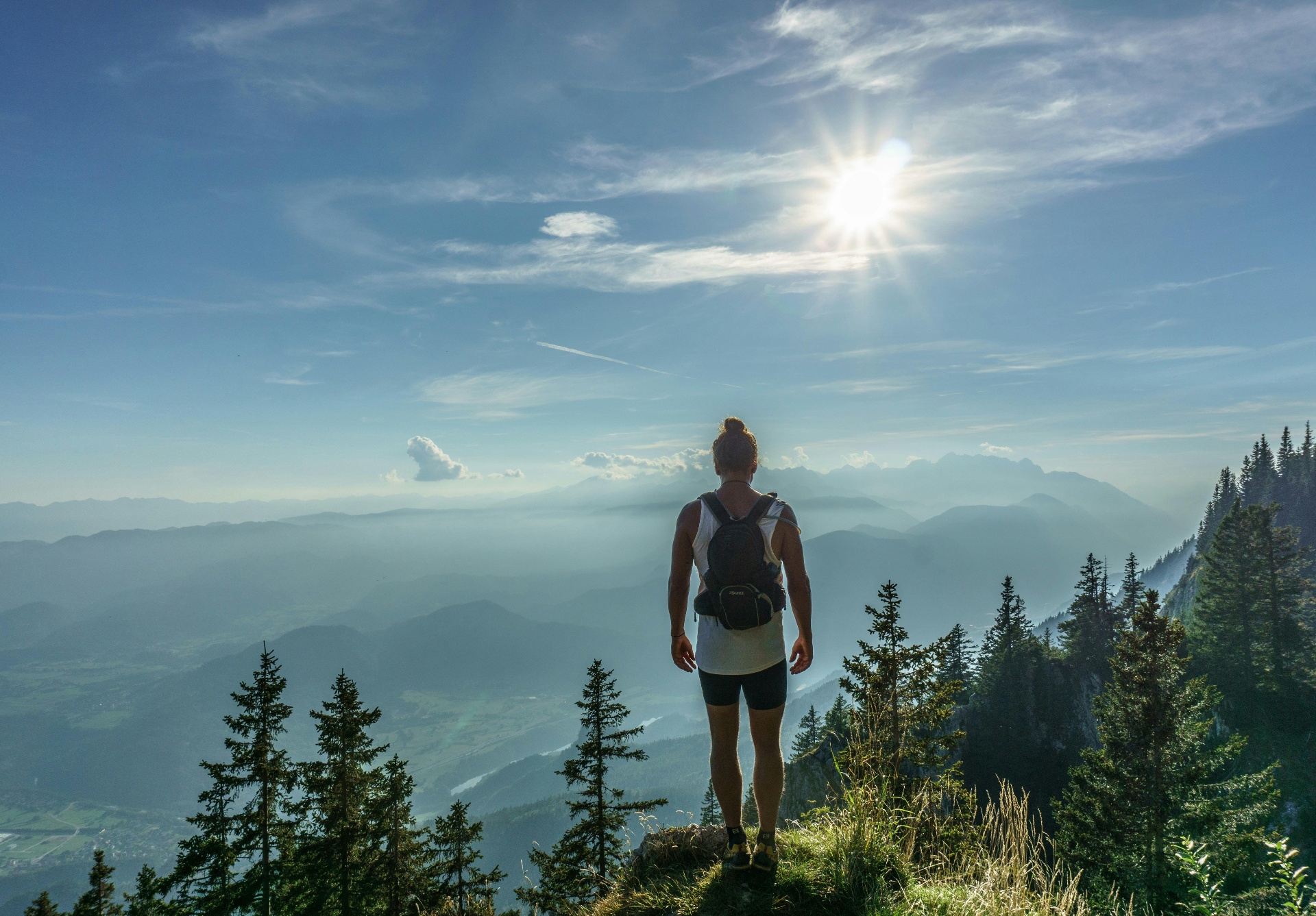 Hiker on mountain summit overlooking valley at sunrise
